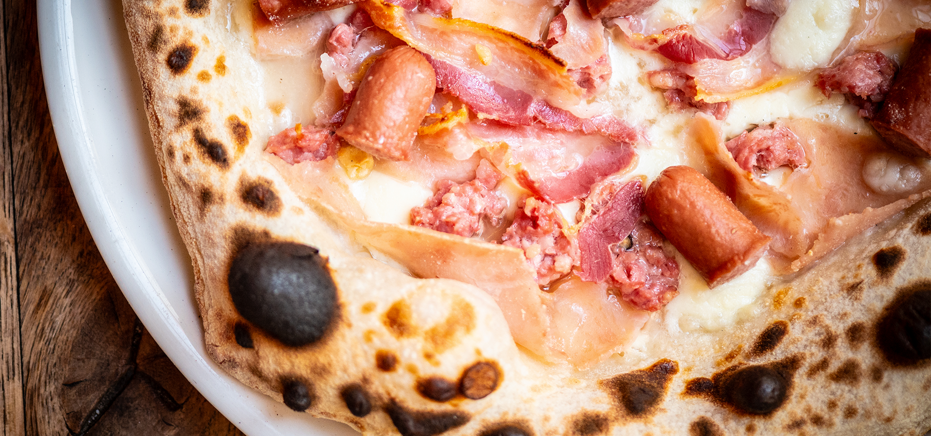 A man in a kitchen preparing a pizza.